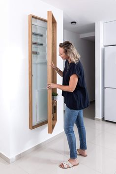 a woman standing in front of a refrigerator opening it's door to look inside