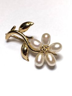 This is a 10K and cultured pearl lapel pin or brooch. The pearls form an attractive flower on this piece of vintage Jewellery. The pin measures 1 1/2 inches long and 3/4 of an inch at the widest point. The pin is hallmarked 10K. It weighs 2.7 grams. Vintage Charm Bracelet, Pearl Flower, Vintage Clock, Vintage Jewellery, Lapel Pin, Solid Yellow, Vintage Charms, Lapel Pins, Brooch Pin