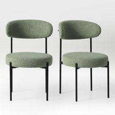 two green chairs sitting next to each other on top of a white floor with black legs