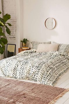 a bedroom with a bed, rug and potted plant