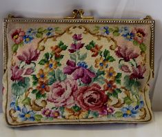 an old purse with flowers on it sitting on a white tablecloth covered shelf next to a wall