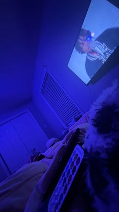 a person laying in bed with a remote control and television on the wall behind them