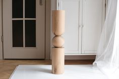 a tall wooden object sitting on top of a hard wood floor next to a white cabinet