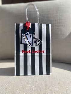 a black and white striped shopping bag with a red ribbon hanging from it's handle