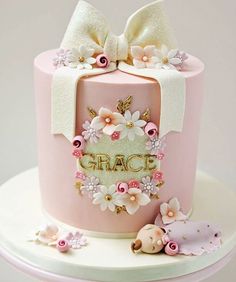 a pink cake decorated with flowers and a name grace on the top is sitting on a table