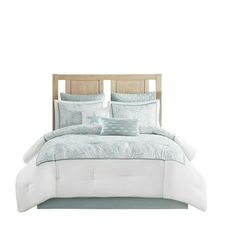 a bed with white and blue comforters on it's headboard, in front of a white background