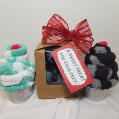 three small knitted cupcakes in front of a box with a red bow