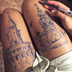 a person with tattoos on their legs holding a pen