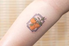 a small tattoo on the arm of a woman with oranges and leaves in it