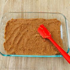 a red spatula sitting on top of a brown cake in a glass baking dish