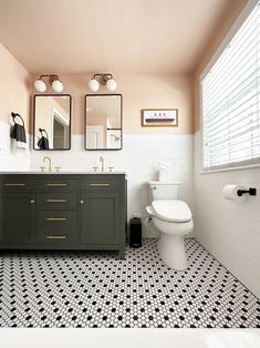 a bathroom with black and white tile flooring and two mirrors on the wall above the toilet