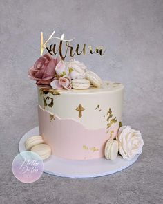 a pink and white cake with flowers on top that says karmin in gold lettering