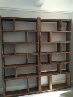 two wooden bookshelves sitting next to each other in a room with white walls