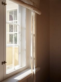 an open window in a room with white walls and curtains on the windows sill