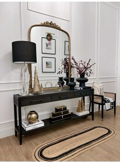 a table with a mirror, vase and other items on it next to a rug