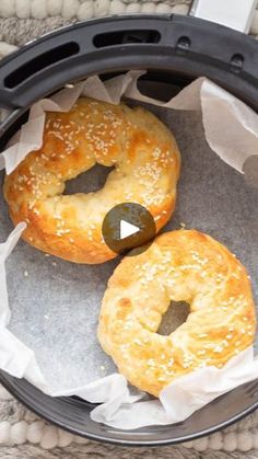 two bagels sitting on top of a pan covered in wax paper next to each other