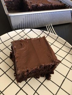 a piece of chocolate cake sitting on top of a white plate next to a metal pan