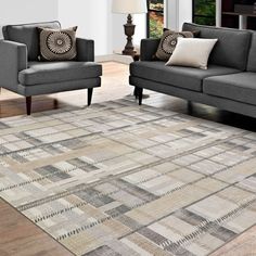 a living room with two gray couches and a rug on the floor in front of a window