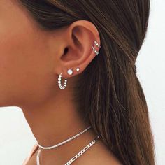 a close up of a woman wearing two different necklaces and earring sets on her neck