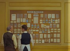 two people standing in front of a bulletin board