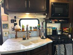 a kitchen with black cabinets and white marble counter tops is shown in front of an open window