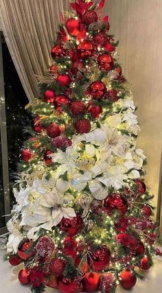 a christmas tree decorated with red and white balls, poinsettis and greenery