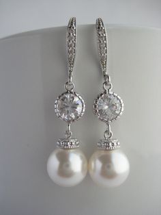 Classic cubic zirconia and pearl bridal earrings in rhodium plated brass setting. Earrings feature 10mm Swarovski white pearl drop that dangles from crystal encrusted ear wire and round cubic zirconia connector. Total length of the earrings is 4 cms . For matching necklace click: https://www.etsy.com/listing/252984768/white-pearl-and-crystal-bridal-necklace?ref=shop_home_active_7 For matching bracelet click: https://www.etsy.com/listing/253901956/classic-bridal-white-pearl-bracelet?ref=shop_home Diamond White Dangle Pearl Earrings For Weddings, White Gold Cubic Zirconia Pearl Earrings For Wedding, Classic Pearl White Cubic Zirconia Bridal Earrings, Silver Pearl Drop Bridal Earrings For Anniversary, Diamond White Sterling Silver Pearl Earrings For Wedding, Anniversary Silver Bridal Earrings With Pearl Drop, Silver Pearl Drop Chandelier Earrings, Silver Cubic Zirconia Dangle Pearl Earrings, Silver Dangle Pearl Earrings With Cubic Zirconia