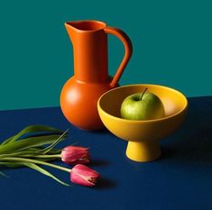 an orange pitcher and yellow bowl next to tulips