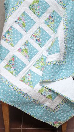 a blue and white quilt sitting on top of a wooden chair