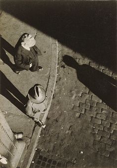 black and white photograph of two people sitting on the sidewalk