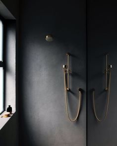 two gold shower faucets are next to each other in a black walled bathroom