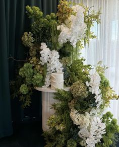 there is a cake decorated with white flowers and greenery on the top of it