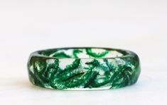 "Crafted with care, this nature-inspired resin band features a beautiful emerald green color that evokes images of lush forests and woodland glades. The faceted design adds texture and dimension to the ring, making it a truly unique and eye-catching piece. The ring is designed to be comfortable to wear, with a smooth finish and a perfect fit. If you choose the \"without flakes\" option for the Faceted Moss Ring, the ring will be made without any metal flakes added to the resin. This means that t Handmade Green Emerald Ring, Nature-inspired, Handmade Nature-inspired Green Emerald Ring, Unique Green Resin Ring, Unique Green Resin Rings, Emerald Green Ring, Moss Ring, Faceted Design, Green Ring, Ring Making