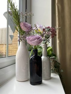 three vases with flowers in them sitting on a window sill