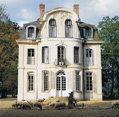 sheep are grazing in front of an old house