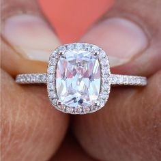 a woman's hand holding an engagement ring with a large white diamond