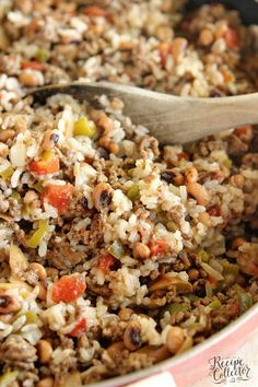 a pot filled with rice and meat next to a wooden spoon