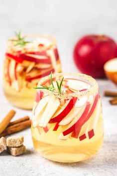 two glasses filled with apple cider and cinnamon sticks