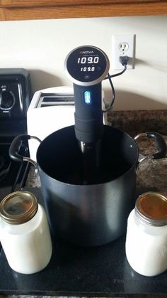 an electric blender sitting on top of a counter next to two jars and a pan