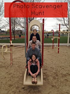 four people are sitting on a slide in the sand at a playground with a sign that says photo scavenger hunt