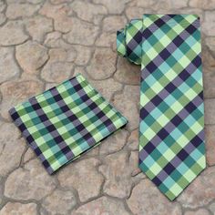 Shades of Green Check Plaid Silk Necktie This elegant silk necktie features a classic check plaid pattern in various shades of green, offering a refined and versatile addition to any wardrobe. The subtle interplay of green hues adds depth and sophistication to your look. Here’s how to best coordinate this necktie with your attire: Dress Shirts: White Dress Shirt: A timeless and clean choice that allows the tie's pattern to stand out. Light Blue Dress Shirt: Adds a subtle contrast that complements the green tones. Gray Dress Shirt: Provides a modern and professional appearance, ideal for business settings. Light Green Dress Shirt: Creates a harmonious look that enhances the tie’s color palette. Suits: Navy Suit: A versatile and elegant option that pairs well with the tie’s shades of green. Elegant Green Tie With Pocket Square, Green Formal Tie With Pocket Square, Classic Green Neckwear For Business, Classic Green Neckwear With Ties, Classic Green Suit And Tie Accessories, Classic Green Neckwear For Gift, Light Blue Dress Shirt, Light Green Dress, Charcoal Suit