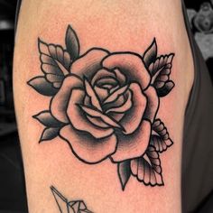 a black and white rose tattoo on the right side of the leg, with an origami bird below it