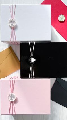 four different colored envelopes tied together with pink string and two silver buttons on each side