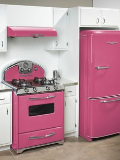 a pink stove top oven sitting next to a refrigerator freezer in a white kitchen