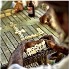 two people playing dominos on a wooden table