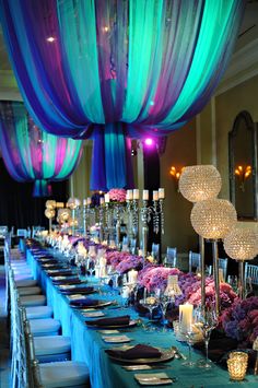 a long table is set up with blue and purple draping over the tables