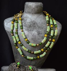 Mesmerizing green layered necklace and matching drop earrings. This stunning set showcases authentic West African beads, expertly crafted into a cascading masterpiece that captures the lush beauty of the region. The multi-strand necklace and elegant earrings blend traditional artistry with contemporary flair, creating a bold statement that's perfect for both everyday wear and special occasions.  Let these pieces' transport you to sun-drenched landscapes and rich cultural heritage. The distance b Traditional Green Multi-strand Beaded Necklaces, Green Multi-strand Jewelry With Colorful Beads, Traditional Green Multi-strand Beads, Elegant Green Double Strand Jewelry, Green Bohemian Double Strand Jewelry, Bohemian Green Single Strand Jewelry, Green Multi-strand Jewelry For Gift, Green Bohemian Single Strand Jewelry, Multi-strand Green Jewelry For Gift