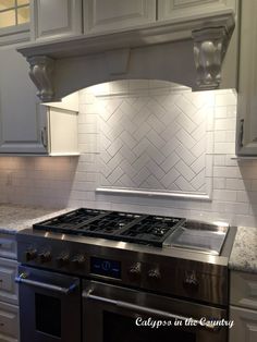 a stove top oven sitting inside of a kitchen next to white cabinets and counter tops