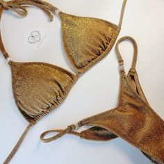 Top quality Bikini. Made in USA 2-3 week turn around time. Made to order Perfect for posing in and practicing in. Great for figure, wellness and bikini division. Also perfect for the beach and taking selfies in. Cute dainty gold rhinestone connector. Top cut is our triangle top, adjustable so you can gather top or not. Bottom back is Pro-cut and V-front cut. Top lined with cup hole for inserts. Bottom front has lining and the back is single layer, with scrunch butt to enhance glutes. Recommend- Hand wash & hang dry. No Refunds, returns and exchanges. Lining is sport lining with MaxDri moisture management & Anti-microbial Content: 80% Nylon, 20% Spandex 92%Polyester- 8% Spandex Metallic Fitted Triangle Top Swimwear, Gold Festival Swimwear, Gold Triangle Top Swimwear For Festivals, Gold Fitted Swimwear For The Beach, Gold Fitted Swimwear For Beach, Fitted Gold Swimwear For Beach, Fitted Gold Swimwear With Triangle Top, Gold Fitted Triangle Top Swimwear, Fitted Gold Triangle Top Swimwear