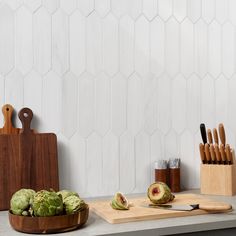 a cutting board with some artichokes and knifes on top of it